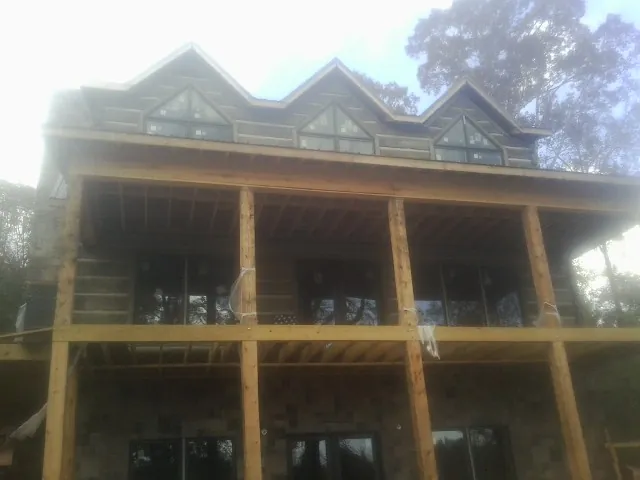 Dormers and porch framing on a large log home under construction — Roof Coating work by our crew in Jasper